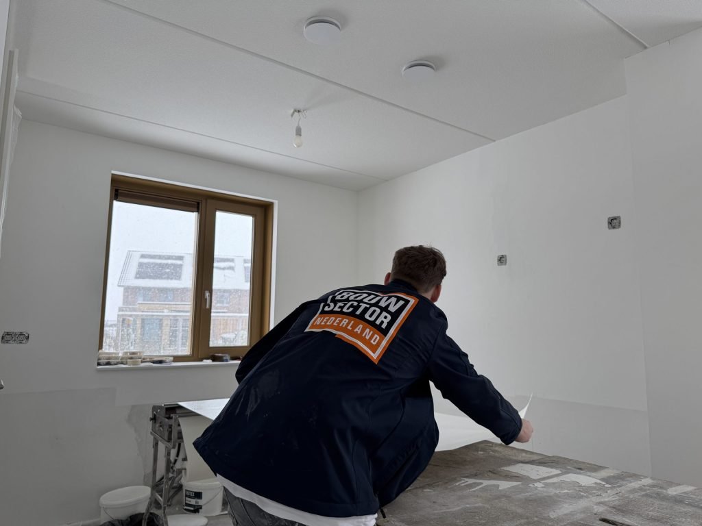 Behanger van Bouwsector Nederland buigt zich over de plaktafel in een kale slaapkamer