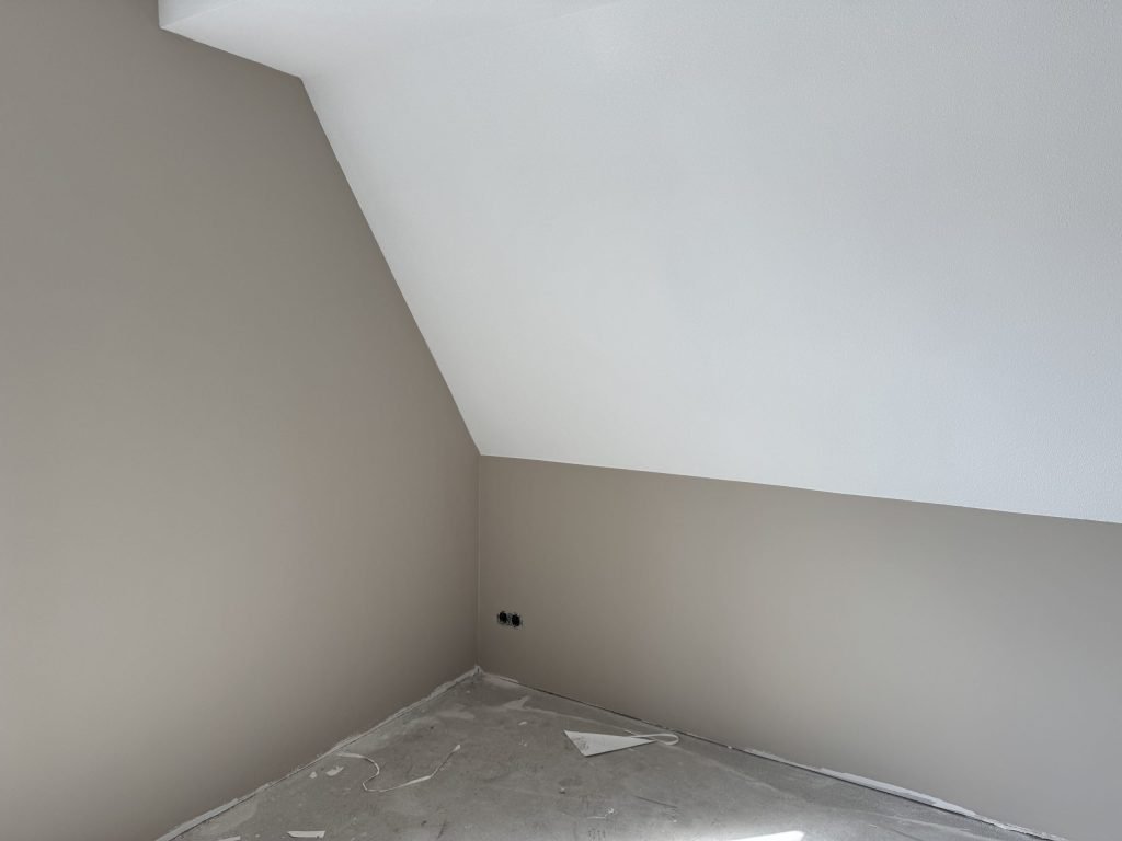 Zolderkamer met een schuine wand en afgewerkte wanden, de vloer nog afgedekt